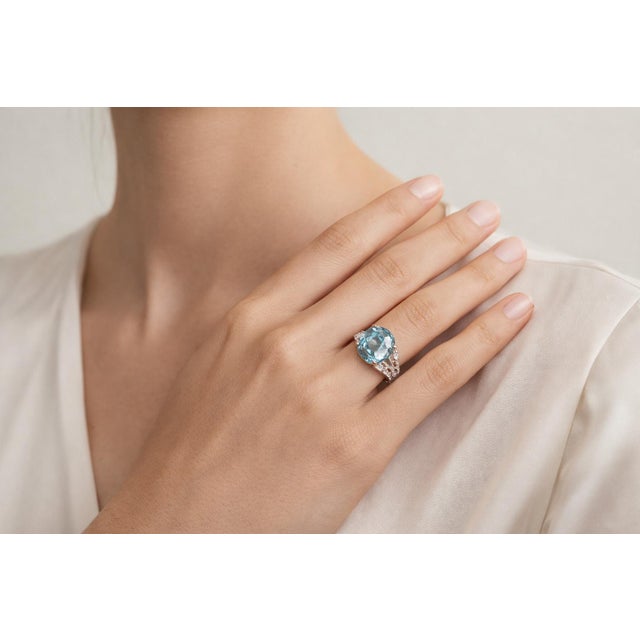 Elegant 18K white gold ring featuring an oval aquamarine center stone weighing 5.70 carats, accented by 16 natural...