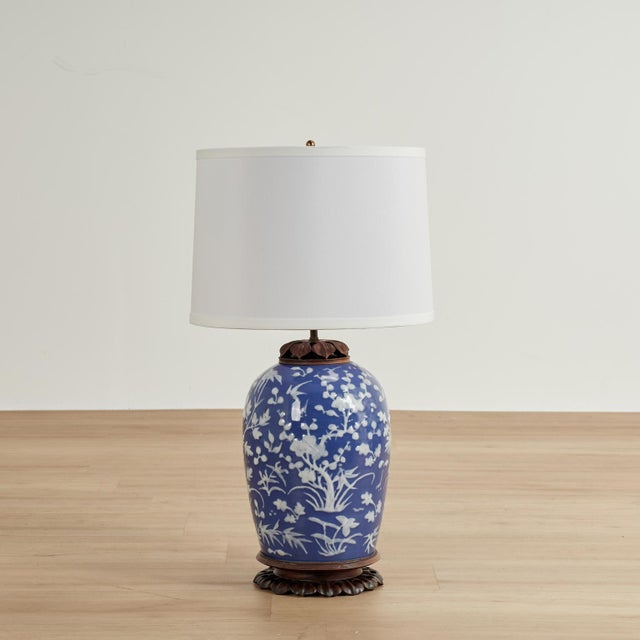 Alluring pair of Chinese porcelain table lamps hand decorated with white floral motifs on a blue background having unique...