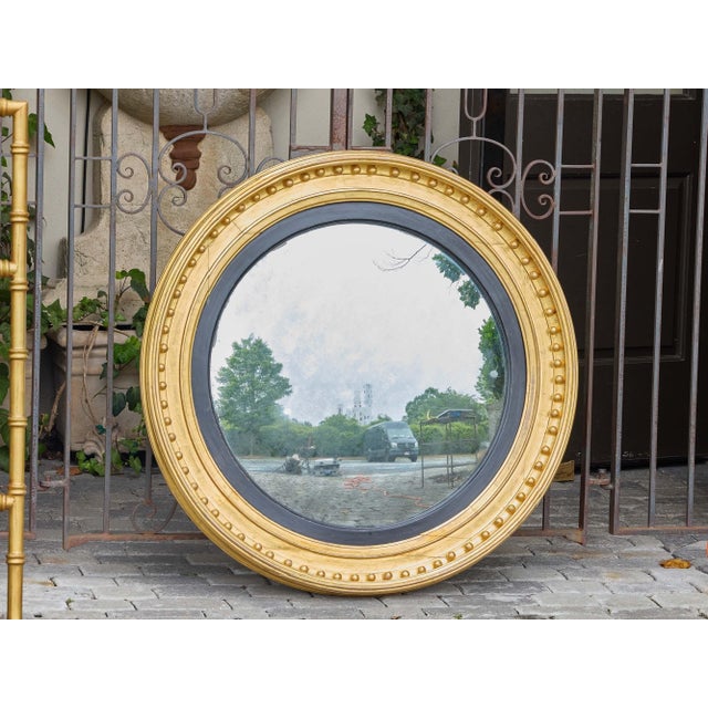 A striking oversized English convex mirror from the 19th century, featuring a beautifully balanced combination of giltwood...