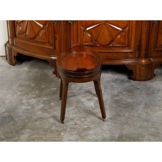 An English mahogany tray top side table from the 19th century, with splaying legs and casters. Created in England during...
