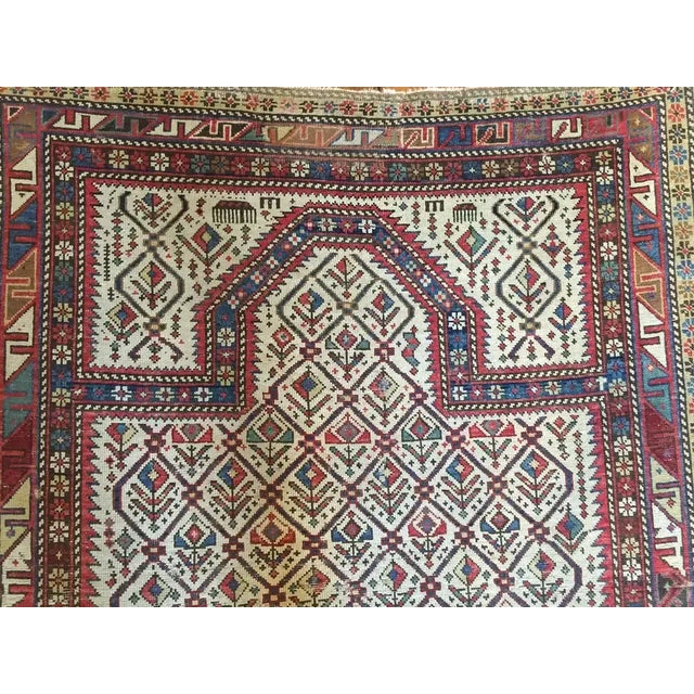 A late 19th century Persian prayer rug with a sweet all-over multicolored floral pattern on a white background surrounded...