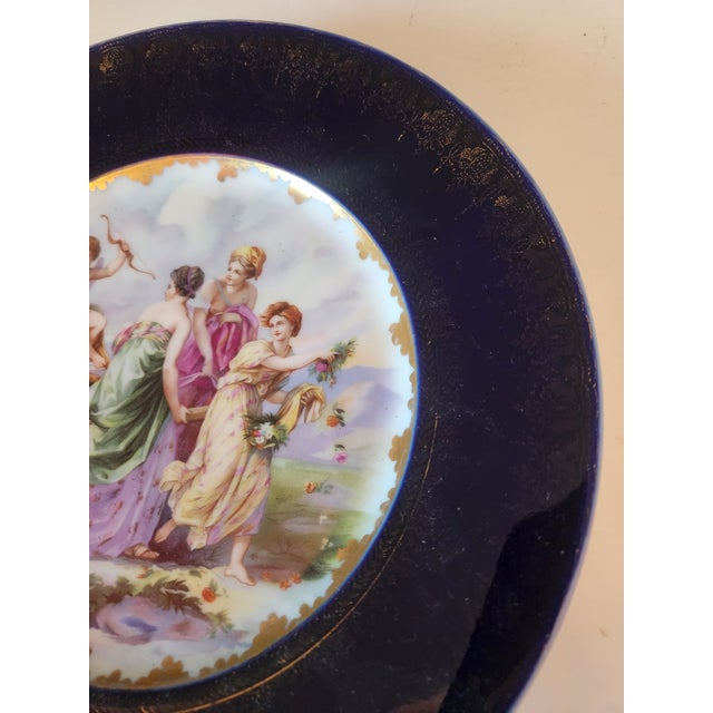 Rosenthal & Co porcelain plate with a scene depicting Cupid and three maidens, possibly titled "Triumph des Amor". The...