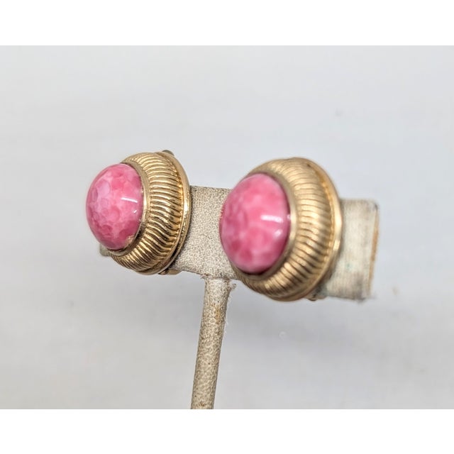 1950s round goldtone cabochon faux-speckled coral center with ribbed edges clip earrings. Marked "Nettie Rosenstein" in...
