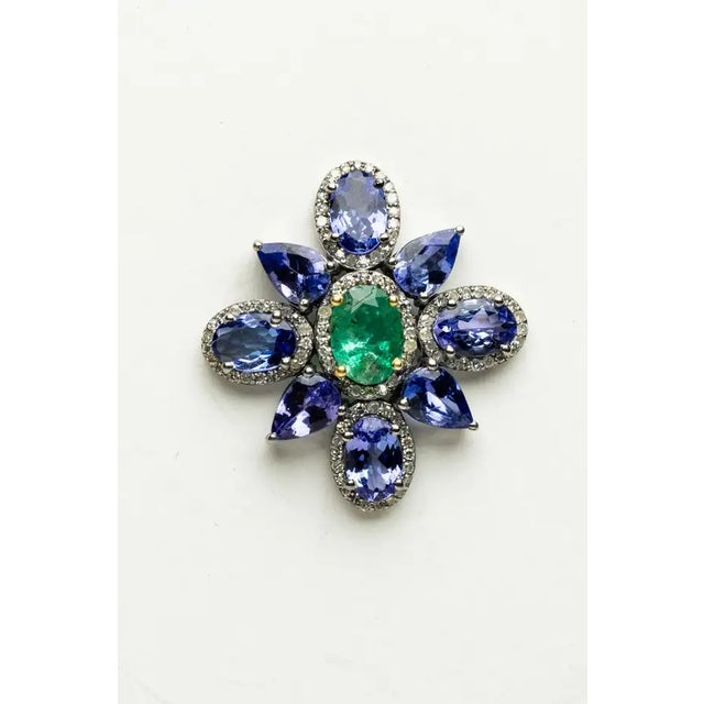 A pair of stunning flower-motif stud earrings featuring a center faceted, oval emerald totaling 1.53 carats and surrounded...