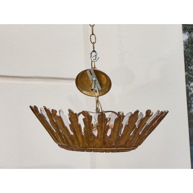 An Italian carved giltwood sunburst chandelier from the early 20th century, circa 1920–1930, featuring a rich finish and...