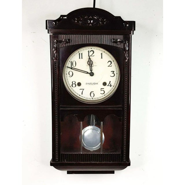 A vintage Ryusuisha wall clock featuring a dark polish wood mahogany - colored clock case. The clock features a scalloped...