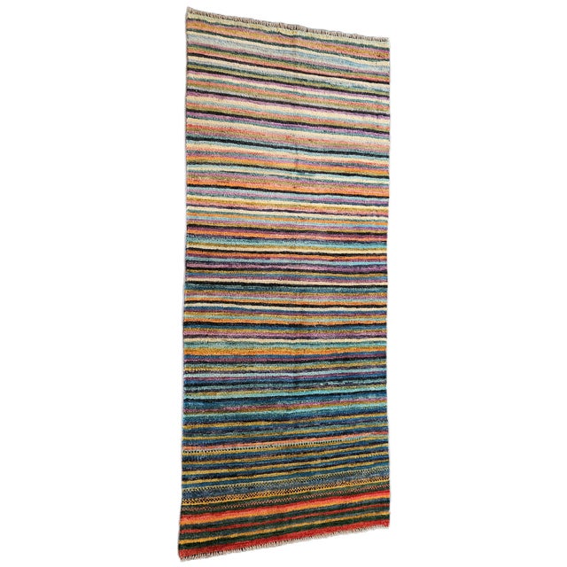 An original hand-knotted Afghan ethnic rug, featuring a vibrant multicolored striped composition that combines shades of...