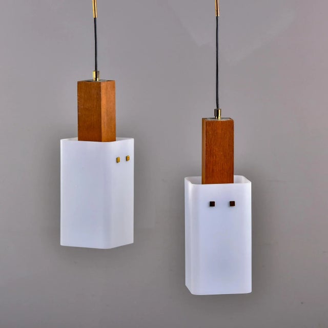 Circa 1960s two light hanging Scandinavian light fixture with rectangular white glass globes, teak bodies and a brass...
