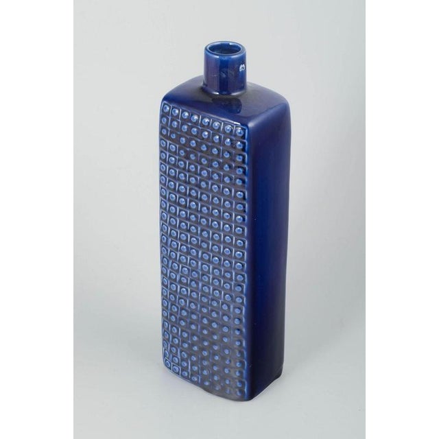 Bengt Berglund for Gustavsberg, Sweden. Tall rectangular stoneware vase with dark blue glaze. One side decorated with a...