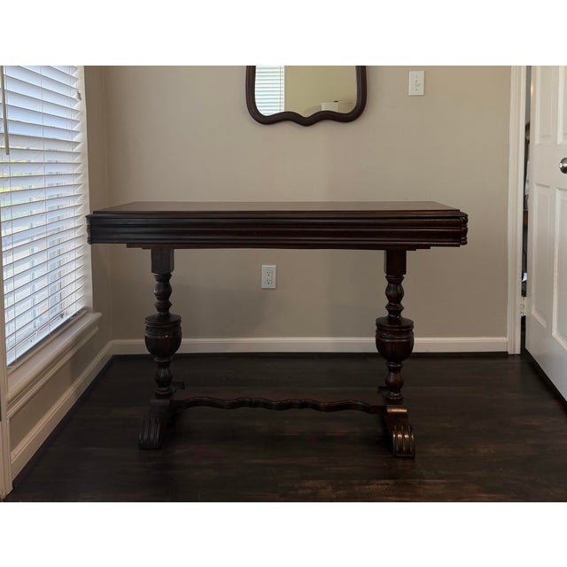 Vintage Jacobean Revival draw-leaf console table featuring turned baluster legs, shaped stretcher, and dark wood finish....
