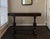 Vintage Jacobean Revival draw-leaf console table featuring turned baluster legs, shaped stretcher, and dark wood finish....