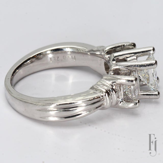 Here is a Platinum Three-Stone Ring featuring a 0.75ct. F/SI1 Princess Cut Diamond Center & Two 0.31ct. F/VS2 Princess Cut...