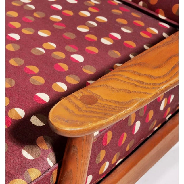 This is a pair of mid-century modern solid teak sculpted arm lounge chairs. They have spindle or slat backs with a loose...