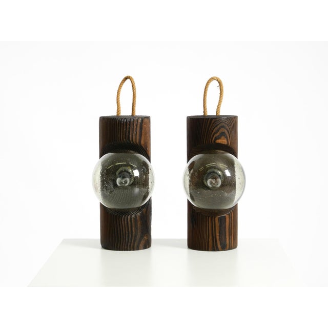 Two rare 1960s table or wall lamps made of dark-stained pine wood with glass spheres. the high-quality glass spheres have...