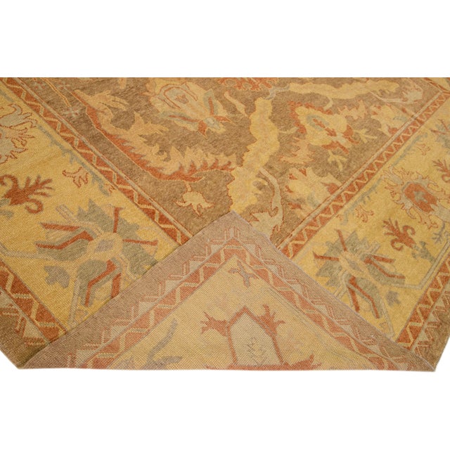 Beautiful modern Turkish Oushak hand-knotted wool rug with a light brown color field. This rug has blue, yellow, and rust...