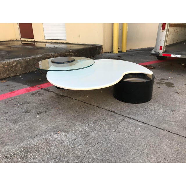 This unique coffee table finished in pearlized white lacquer and black column style legs the glass top section rotates to...