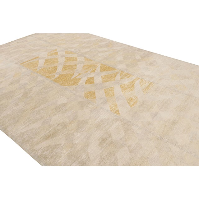 Hand-knotted in wool and silk, this 10x14 Scandinavian rug in beige, gray and gold, features geometric patterns inspired...