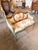 A charming French Louis XVI-style canapé settee featuring a carved sage-green wood frame, soft floral upholstery, and...