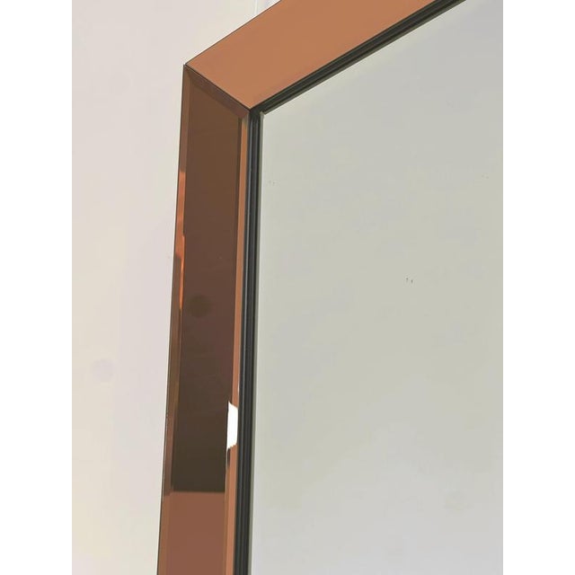 Elegant vintage wall mirror featuring a wide frame composed entirely of peach/rose-bronze tinted mirrored glass. The four...