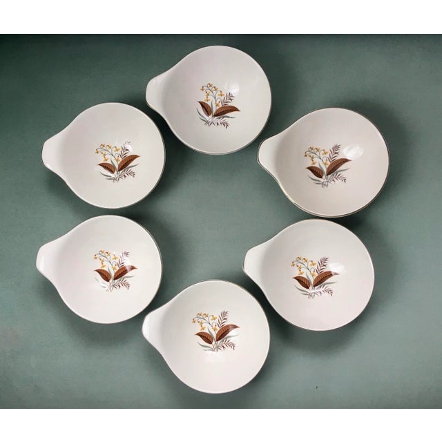 A classic set of handled cereal bowls with an atomic nature print center in neutral shades.