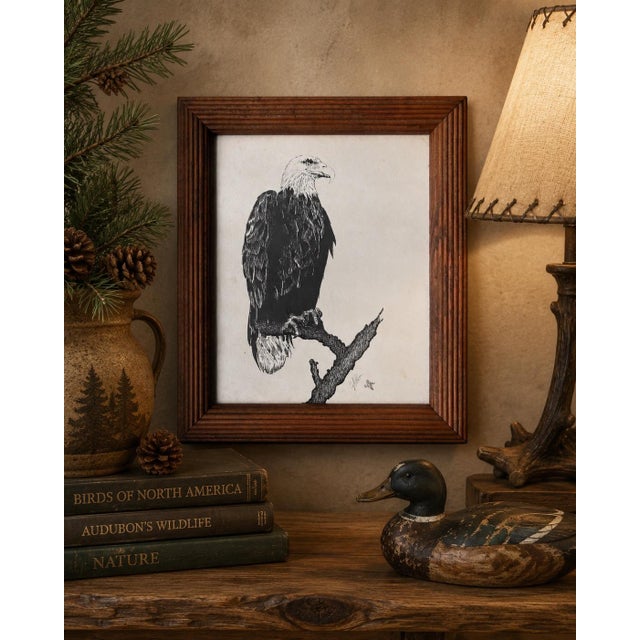 A beautifully framed signed wildlife print depicting a majestic American Bald Eagle perched on a weathered tree branch by...