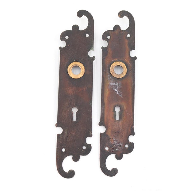 Traditional style swirl door backplates made of brass with a japanned finish. The original mounting screws are not...