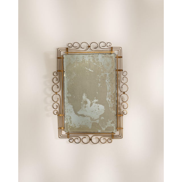 A refined Art Deco mirror with a brass frame, characterized by geometric clarity and symmetrical proportions. The warm...