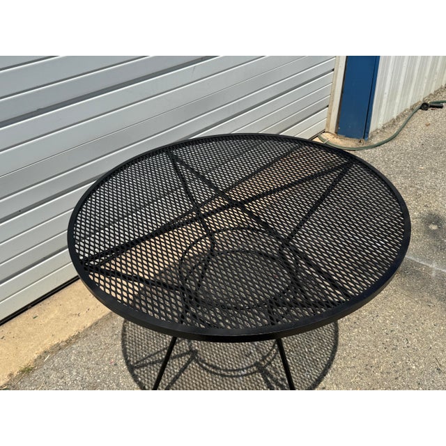Classic vintage wrought iron patio table featuring a round expanded metal mesh top and sculptural iron base. Believed to...