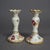 An antique German pair of candlesticks offer porcelain construction with hand painted floral decoration and gilt...