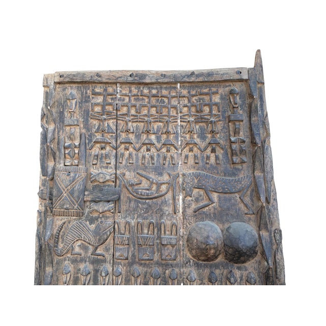 This vintage Dogon granary door from Mali features intricate carved relief figures— standing Nommo ancestors and animals...