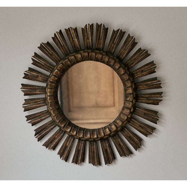 Vintage French sunburst mirror. This sunburst wall hanging mirror features gilt "rays" coming out of a central round...