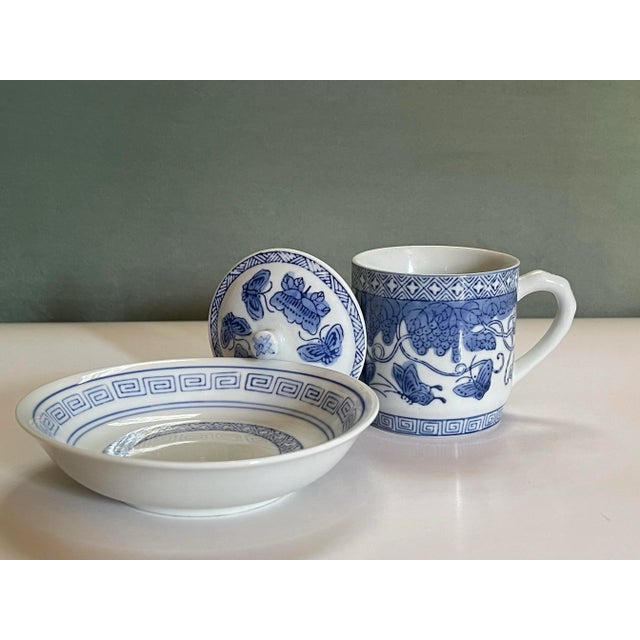 A beautiful lidded mug with small ceramic bowl shaped saucer in a geometric pattern featuring grapes, flowers and...