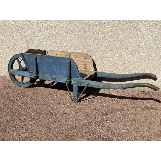 Old wooden wheelbarrow color blue of Nimes, wooden wheel circled with iron.