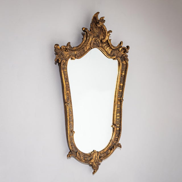 Wall mirror in an asymmetrical Rococo-style frame with a golden patina.