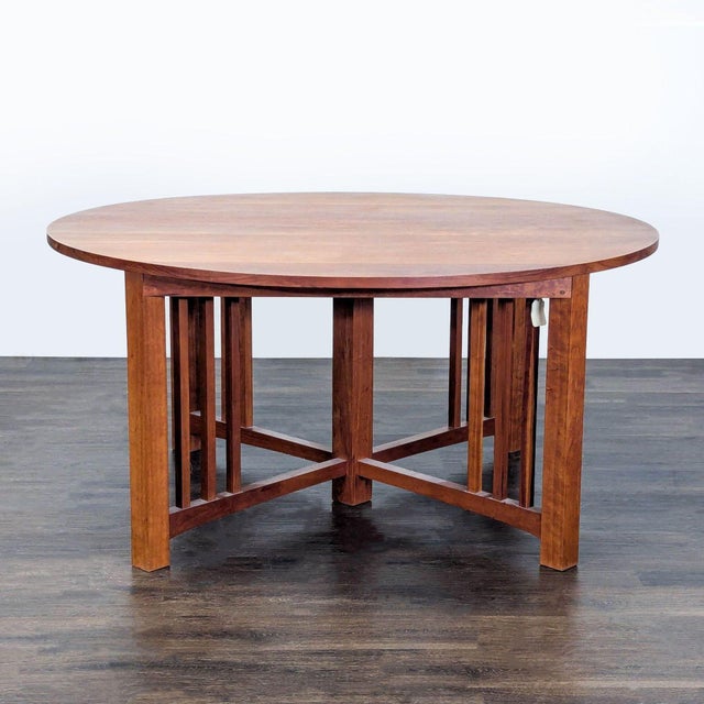 This Thos Moser dining set features a round cherry wood table with two leafs and eight matching chairs. The chairs have...