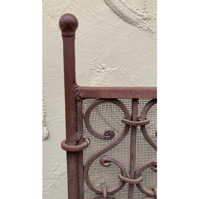 American wrought iron free standing fire screen with flanking ball finials, decorative scrolled centered panel with...