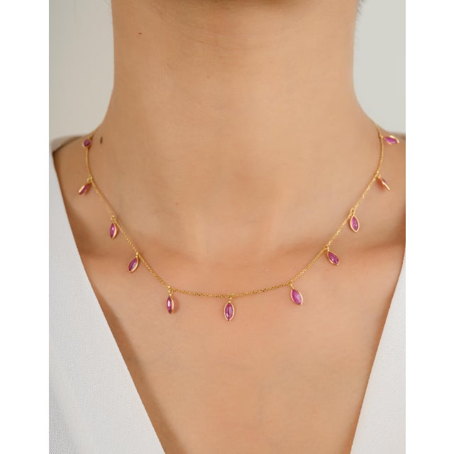 This modern necklace showcases a stunning marquise-cut ruby, gracefully suspended from an 18k yellow gold chain. The sleek...