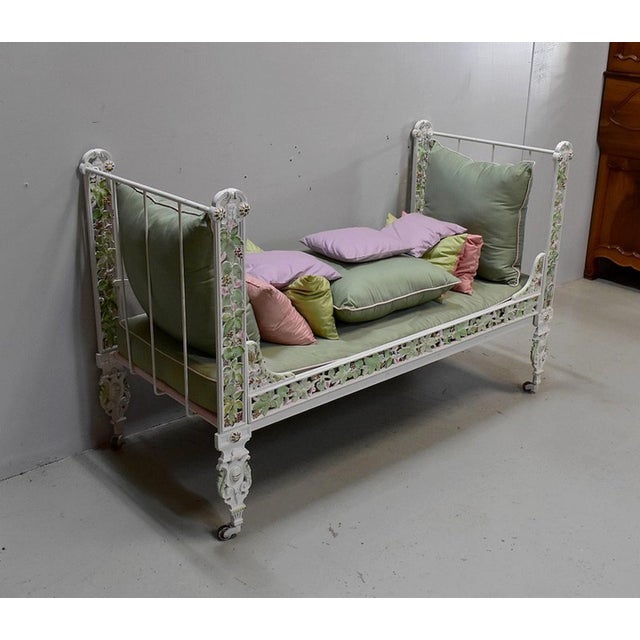 Small rest bench /child's bed in cast iron. Its structure painted in white is richly decorated with beautiful pampres of...