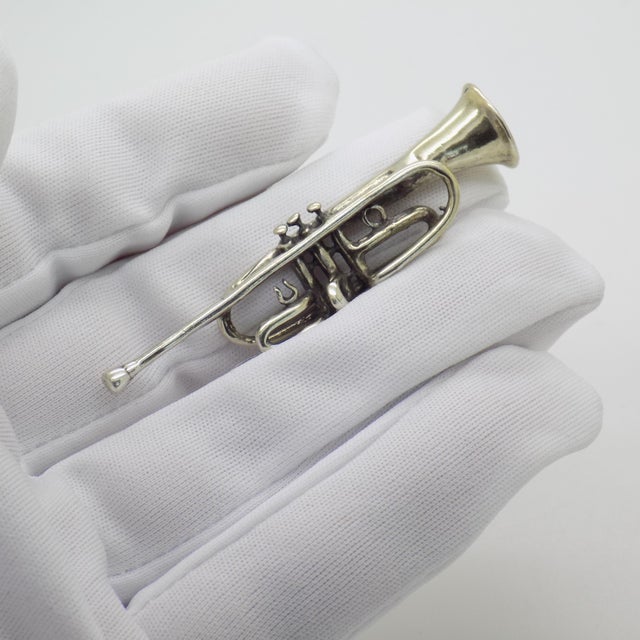 This vintage silver miniature depicts a classic brass wind instrument, the trumpet, scaled as a desktop display novelty or...