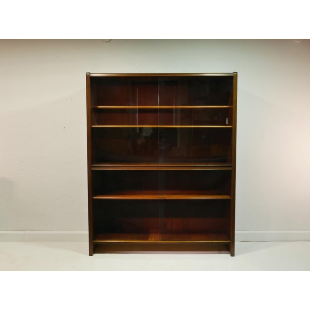A simple and elegant vintage display cabinet from the 1960s with a warm wood tone and classic mid-century design. This...