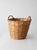 This vintage woven basket features a tall tapered form with double wrapped handles and a braided rim detail. The warm...