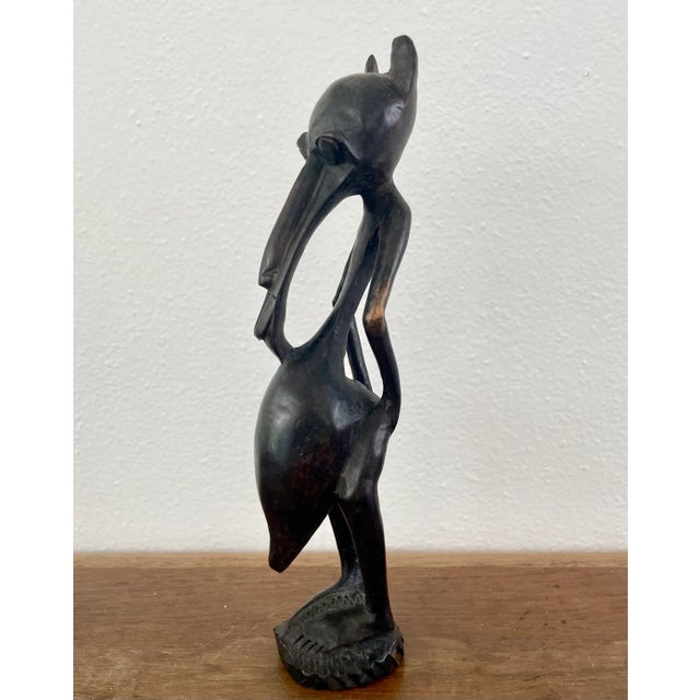 This mid century African wooden figure depicts a man wearing a hyena type animal mask with a long face and snout and...