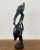 This mid century African wooden figure depicts a man wearing a hyena type animal mask with a long face and snout and...