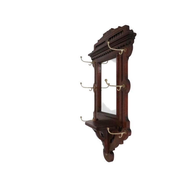 Victorian Eastlake, Aesthetic Movement, wall mirror with brass coat, hat, scarf, hooks. The wood frame is solid walnut,...