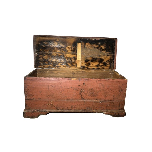 Brick red painted chest. Wood rustic with strap hinges on faded bracket feet. Wood is old; 6 board pine chest.