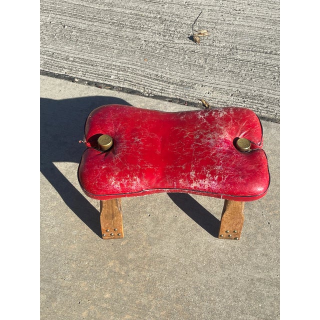 Vintage red and black leather Camel Saddle Footstool with brass accents.