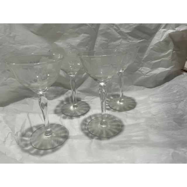 Set of four elegant cocktail stem glasses with cut roses and leaves.