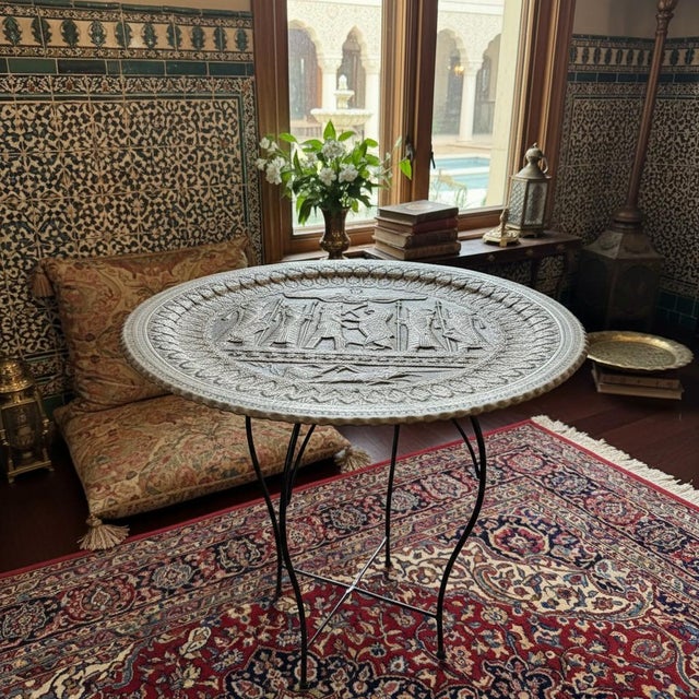 A striking Persian Revival tray table featuring a hand-hammered metal tray, likely tinned copper, with a softly aged...