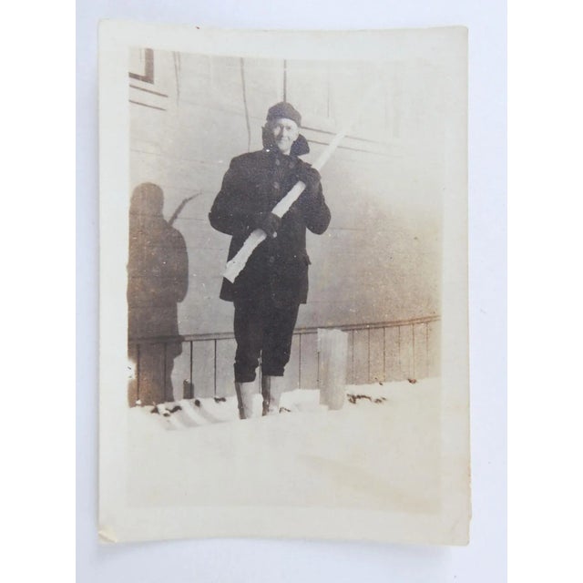 Circa 1920's snapshot photograph of man holding giant icicle. Unframed, corner bumps.