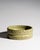 A deeply textured Italian ceramic bowl with carved geometric decoration and a matte pistachio-green glaze. The incised...